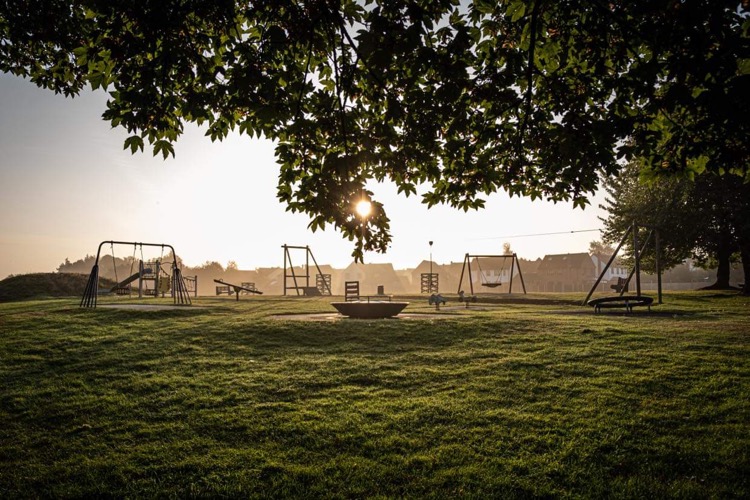 photo of the play equipment at sunset from beneath a tree in Rye Mill Lane play park